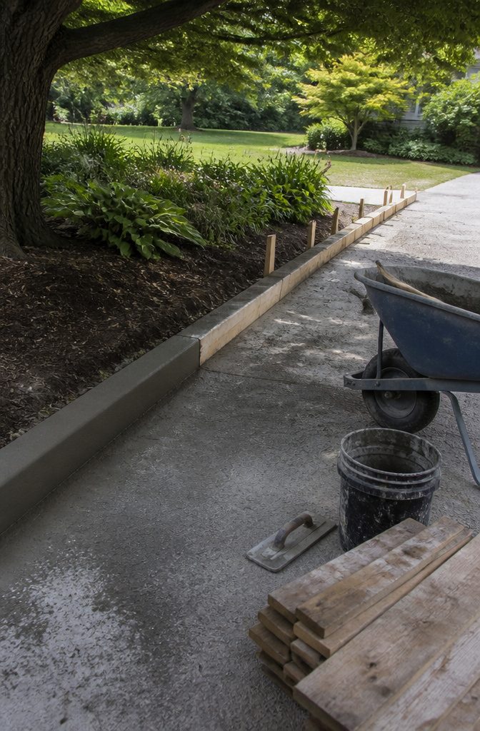 How to Build a Concrete Curb in 7 Steps 11 Fresh curb pour beside smoothed concrete with forms and tools nearby