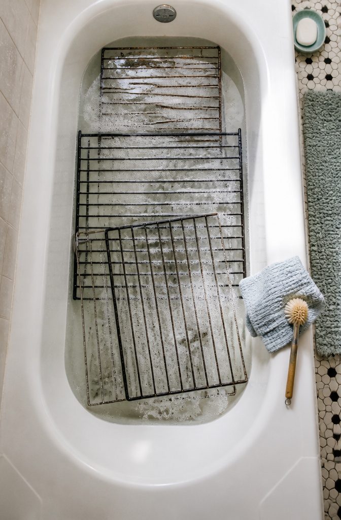How to Clean a Greasy Oven in 8 Steps 8 Metal oven racks soaking in a bathtub filled with hot soapy water