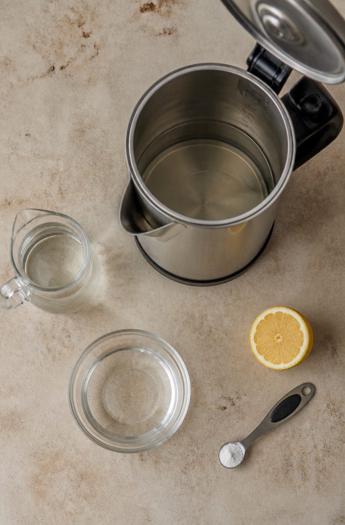 How to Clean an Electric Water Boiler in 6 Steps 3 Electric kettle partly filled with a clear cleaning solution on a kitchen counter