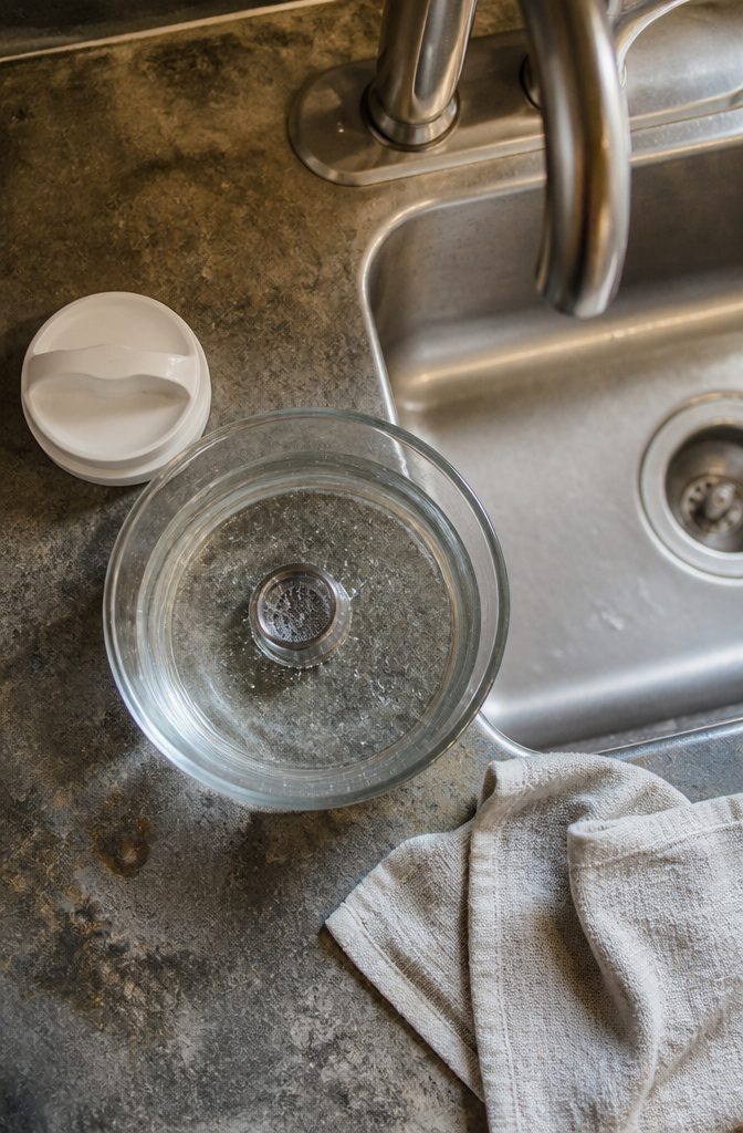 Removable faucet aerator resting in a bowl of vinegar and water